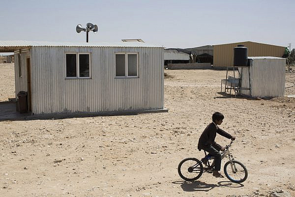 A child rides a bicycle next to a mosque in the Bedouin village of Bir-Hadaj, Negev desert, April 27, 2014. (Activestills.org)