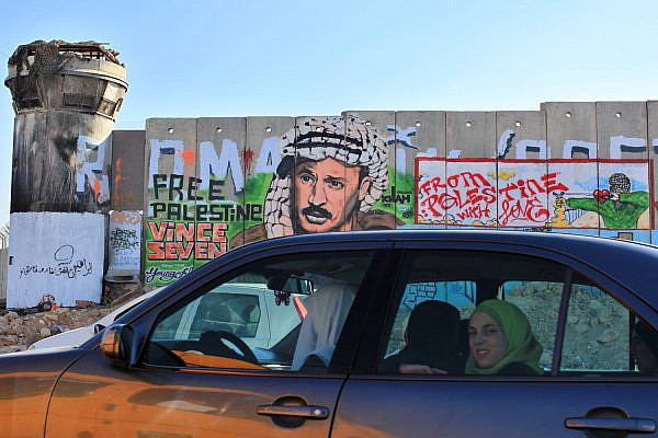 Palestinians in a car pass the separation wall at the Qalandiya checkpoint between the West Bank city of Ramallah and Jerusalem, on Aug 18, 2009. (Kobi Gideon/Flash90)