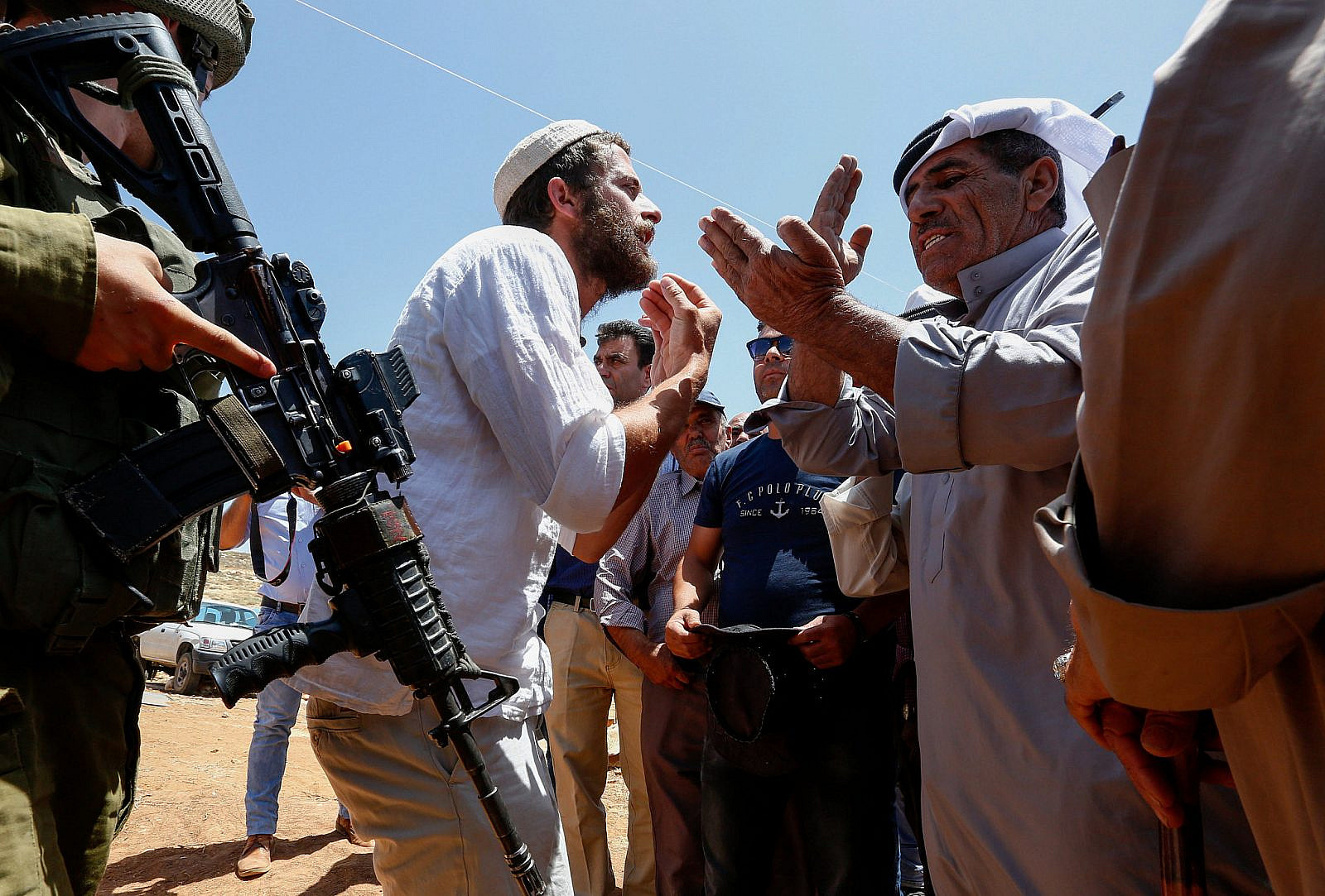 An Israeli settler argues with Palestinians during a protest against a new tent placed by Israeli settlers near Pnei Hever settlement, in the West bank village of Bani Naem on June 23, 2018. (Wisam Hashlamoun/Flash90)