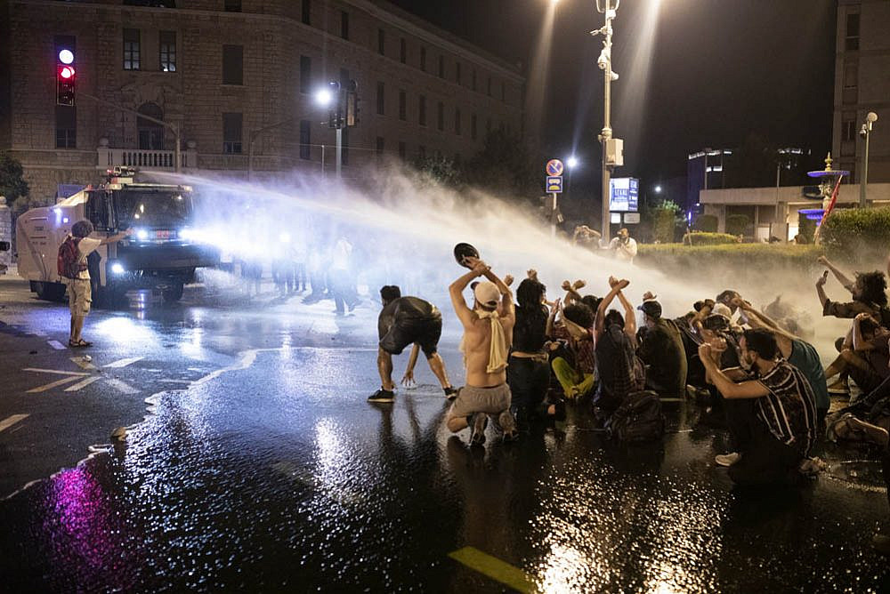 A police water cannon douses dozens of protesters in central Jerusalem during clashes that followed a mass demonstration outside the Prime Minister's Residence, July 14, 2020. (Oren Ziv)