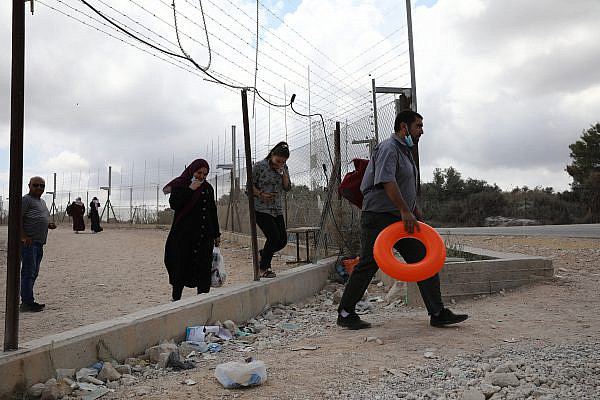 Palestinians walking through a hole in the Israeli separation barrier next to the West Bank village of Far’oun near Tulkarem. (Activestills)