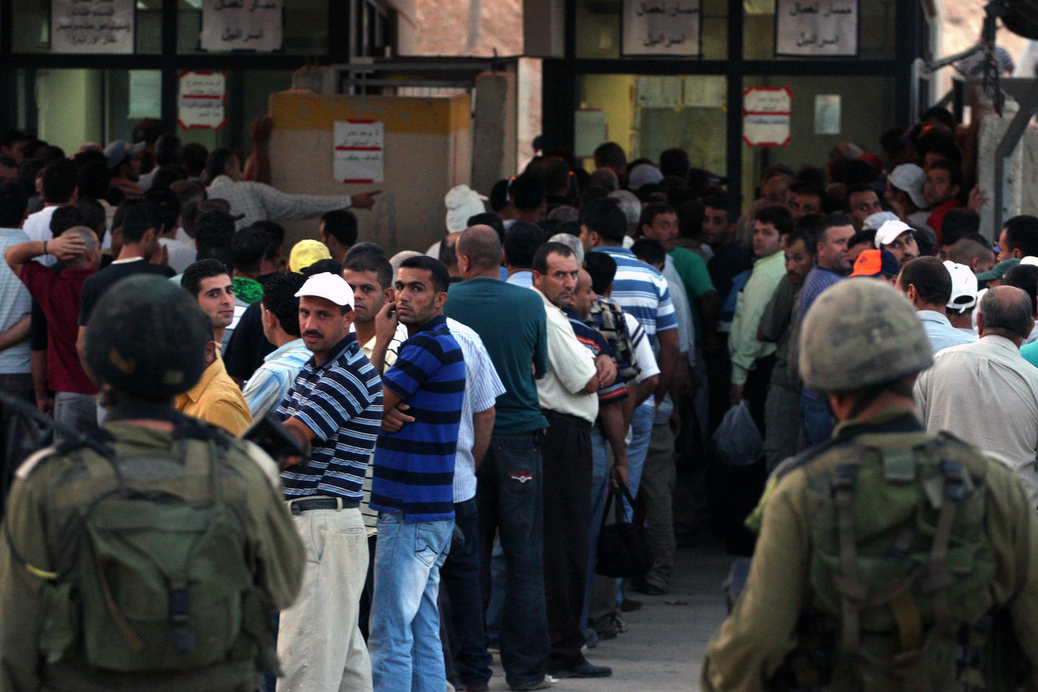 Palestinian workers wait to cross the Isreali-controlled Ni'lin checkpoint, between the West Bank and the Jewish settlement of Modi'in Illit, as they head to work in Israel and nearby settlements on October 4, 2010. (Issam Rimawi/Flash90)