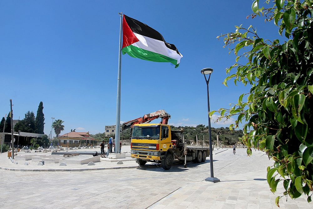 Palestinian workers working on the newly-installed flagpole at the public plaza of the town of Sebastia, West Bank, August 24, 2020. (Ahmad al-Bazz/Activestills)