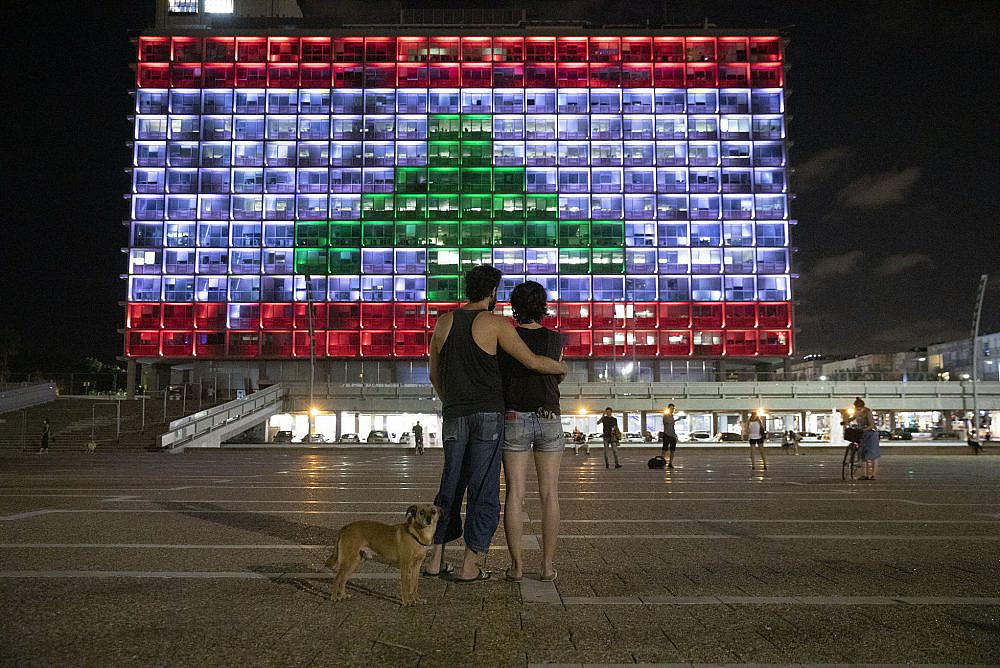 An Israeli couple watches as the Tel Aviv City Hall lights up in the color of the Lebanese flag, following a devastating explosion at the port of Beirut, August 5, 2020. (Orly Noy)