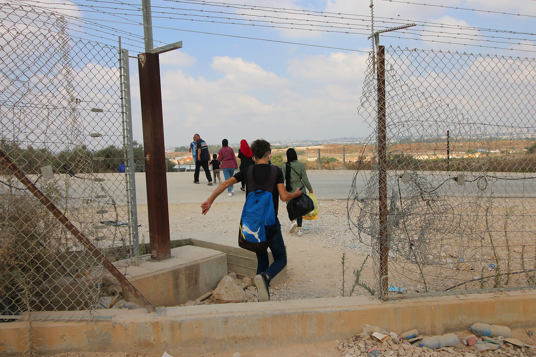 Palestinians walking through a hole in the Israeli separation barrier next to the West Bank village of Far’oun near Tulkarem. (Ahmad Al-Bazz/Activestills)