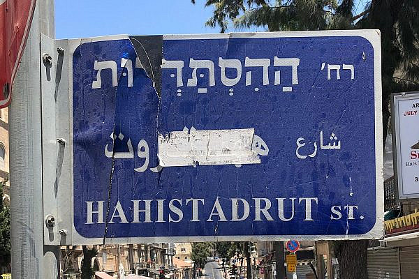 A sticker has been removed but the Arabic remains hidden on a street sign along the central King George Street in Jerusalem. (Ben Reiff)