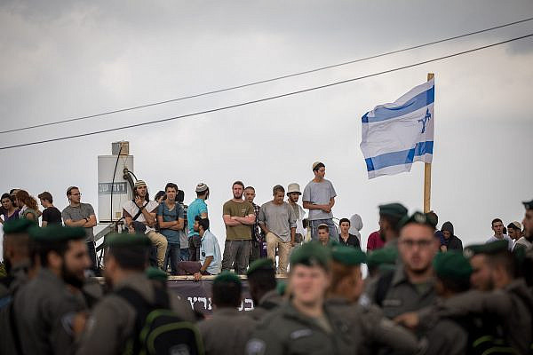 Israeli Border Police guard as settlers stand on a rooftop in the Jewish neighborhood of Netiv HaAvot in Gush Etzion, June 12, 2018. (Yonatan Sindel/Flash90)