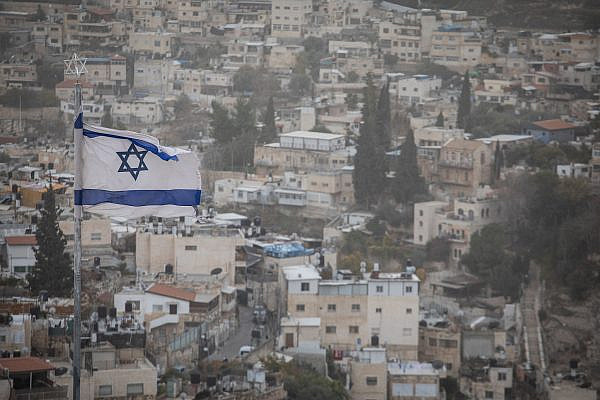 An Israeli flag over the East Jerusalem neighborhood of Silwan, seen from the Mount of Olives, December 25, 2019. (Hadas Parush/Flash90)