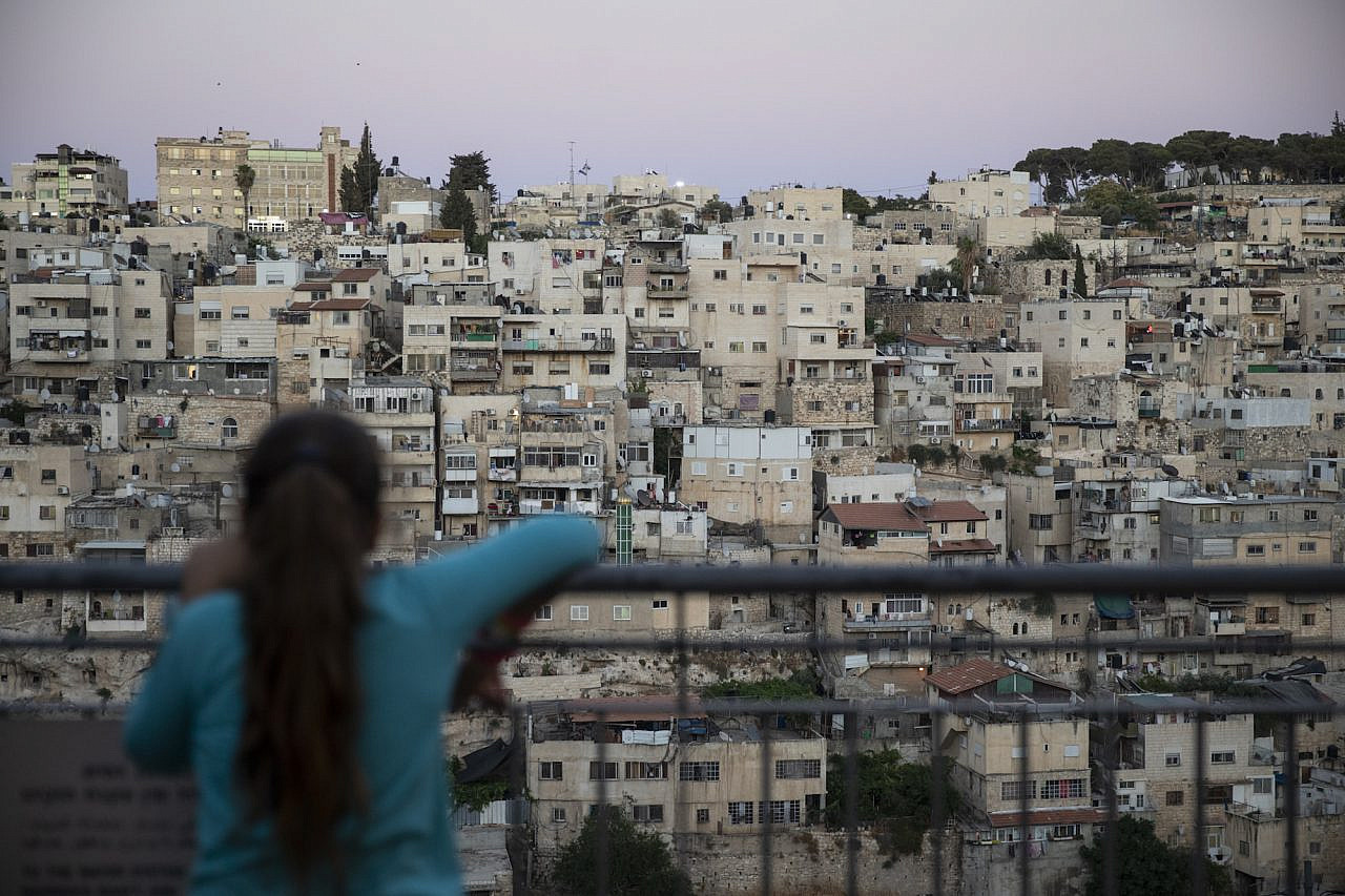 A young Jewish girl looks out from City of David National Park at the Palestinian neighborhood of Silwan, East Jerusalem, July 14, 2019. (Hadas Parush/Flash90)