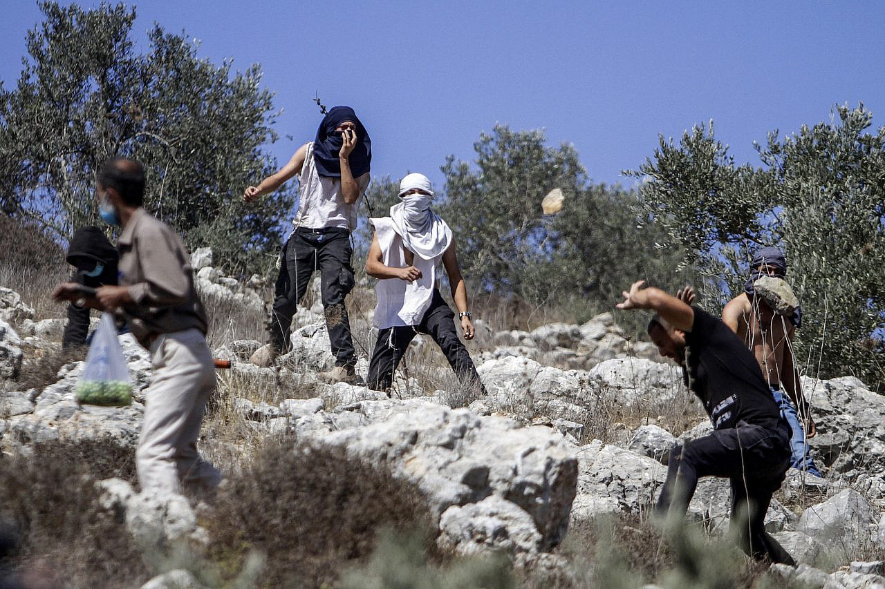 Colonos israelís arroxan pedras aos palestinos durante a tempada de colleita anual preto do asentamento israelí de Yitzhar en Cisxordania o 7 de outubro de 2020. (Nasser Ishtayeh/Flash90)