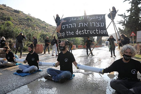 Israeli climate and human rights activists chain themselves to the entrance of HeidelbergCement quarry in the occupied West Bank to protest a government plan to expand the quarry and build an industrial zone nearby, November 22, 2020. (Oren Ziv)