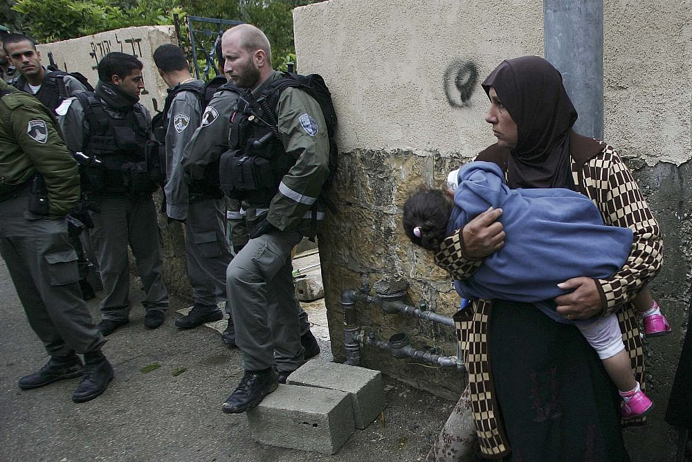A Palestinian woman stands next to Israeli Border Police near the gate of a house in the East Jerusalem neighborhood of Sheikh Jarrah from which a Palestinian family was evicted on November 03, 2009. (Mohamar Awad/Flash90)