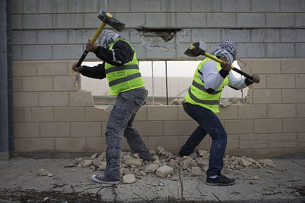 Palestinian activists destroy part of the separation wall in the West Bank village of Bir Nabala, near Ramallah, Nov. 15, 2013. (Activestills)
