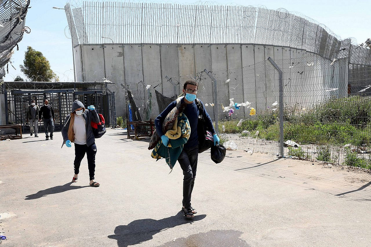 Palestinian workers cross back from Israel at a checkpoint near the West Bank city of Hebron, on April 23, 2020. (Wisam Hashlamoun/Flash90)