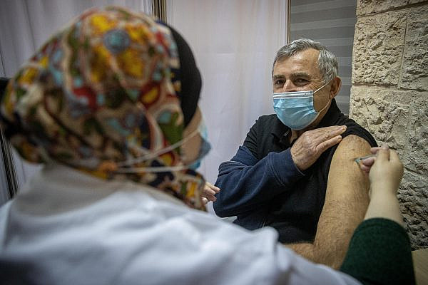 Israelis receive the COVID-19 vaccine at a vaccination center in Jerusalem, on December 24, 2020. (Yonatan Sindel/Flash90)