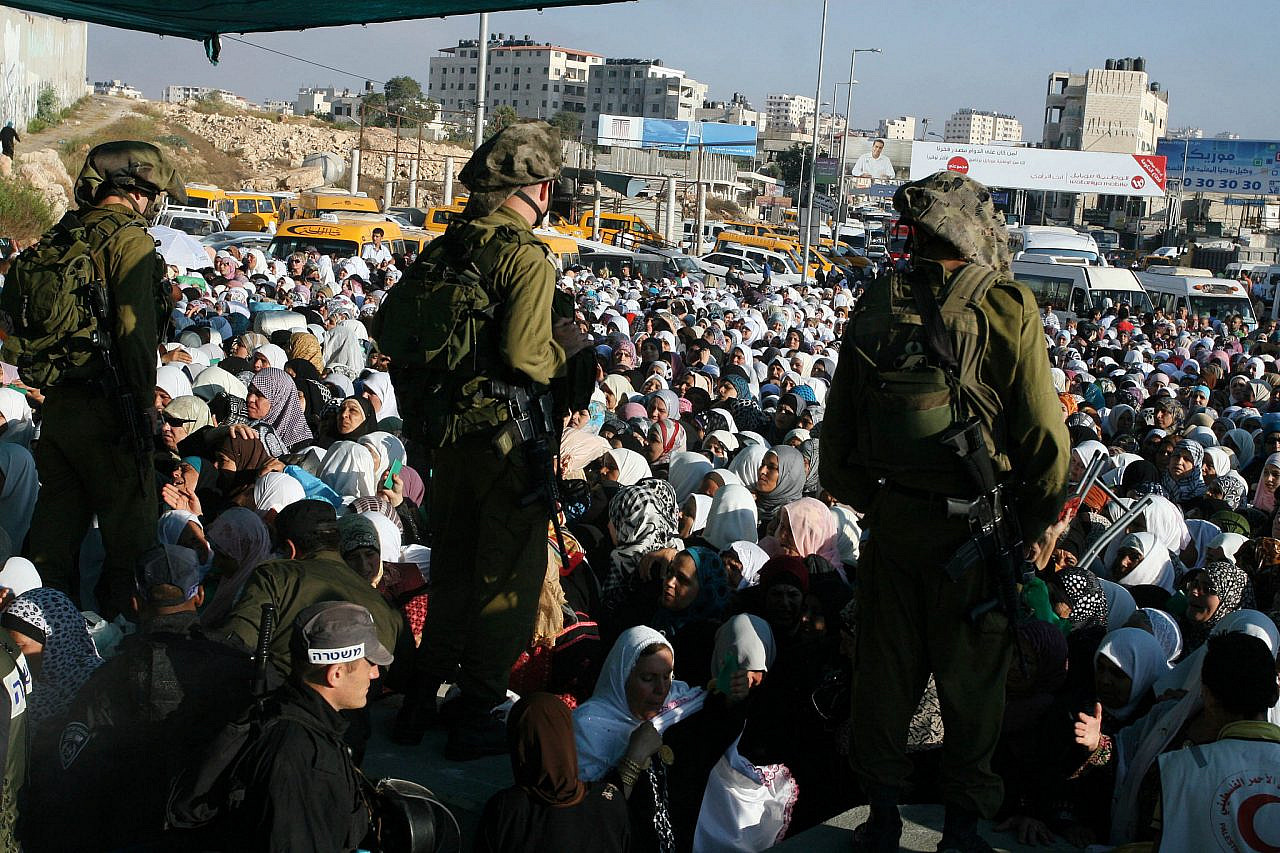 Israeli soldiers checking IDs of Palestinian women as the wait in line to pass the Qalandia checkpoint from Ramallah to Jerusalem, Aug. 19, 2011. (Issam Rimawi/Flash90)