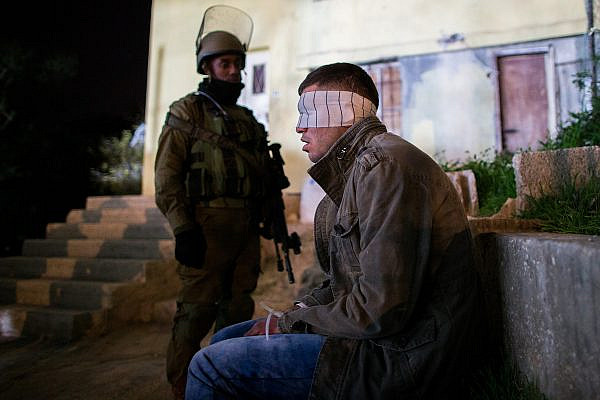 Nachshon Battalion soldiers watch over a Palestinian detainee during an operation of arresting suspects in the Dheisheh Refugee Camp, near the West Bank city of Bethlehem, Dec. 8, 2015. (Nati Shohat/Flash90. )