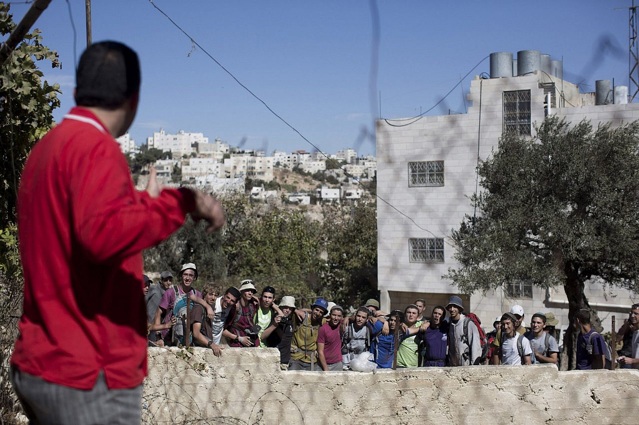 Issa Amro, a coordinator of the group "Youth Against Settlements," looks at Israeli settlers during a tour in the Tel Rumeida neighborhood in the West Bank city of Hebron, October 25, 2013. (Activestills)