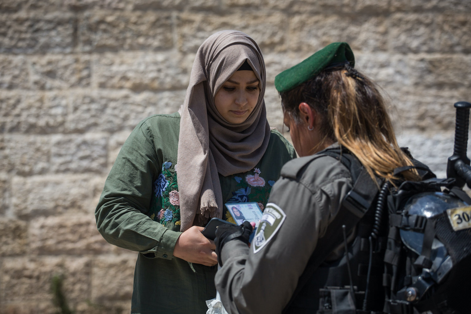 An Israeli Border Police officer checks the ID card of a Palestinian woman in front of Damascus Gate in Jerusalem's Old City, on June 18, 2017. (Hadas Parush/Flash90)