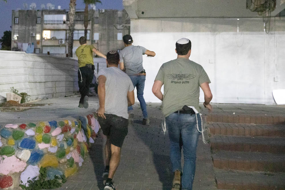 Settlers and right-wing activists run through the city of Lyd in central Israel, May 13, 2021. Many of the settlers came from settlements in the occupied West Bank and spent the evening attacking Palestinians in the city under the eye of Israeli security forces. (Oren Ziv)