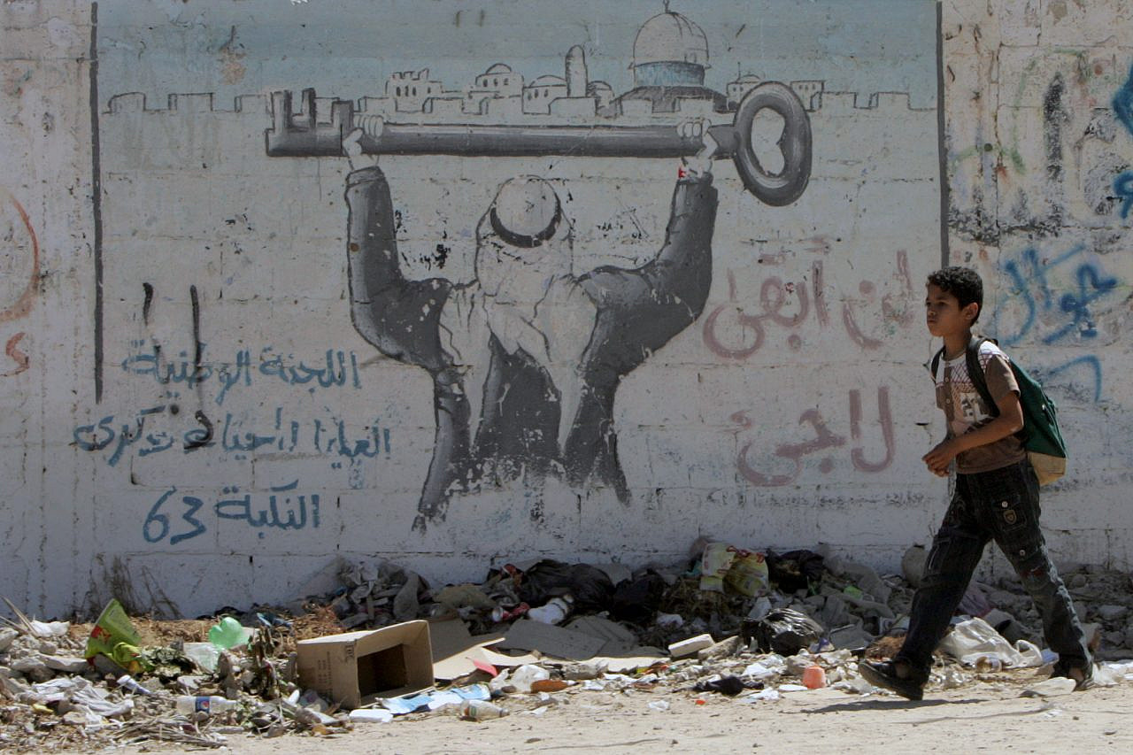 A Palestinian boy walks in front of graffiti that reads 'Returning' as Palestinians attend "Camp of Return" to mark refugees' ties to their lost land, in Rafah, southern Gaza Strip, May 12, 2013. (Abed Rahim Khatib/Flash90)