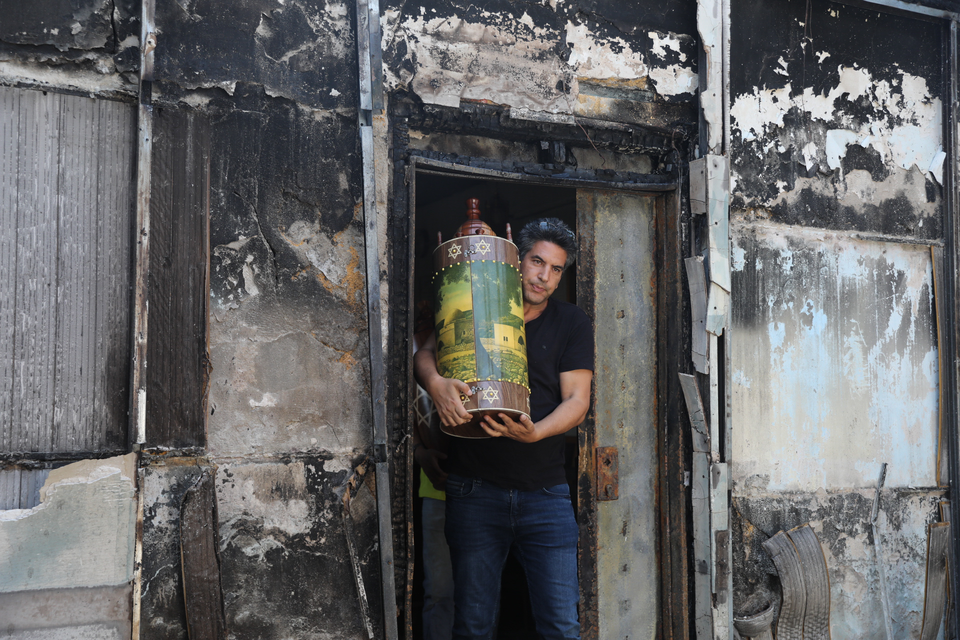 Israelis carry out torahs from a synagogue burned down by Palestinian residents in Lydd, central Israel, May 12, 2021. (Yonatan Sindel/Flash90)
