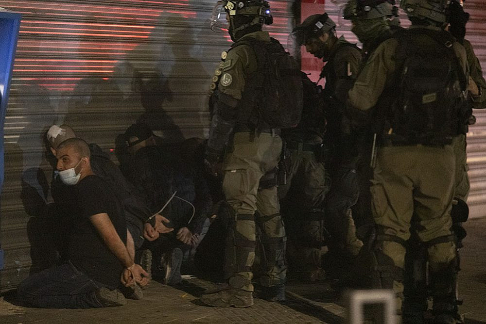 Israeli officers blindfold a Palestinian citizen of Israel during violent confrontations in Lydd, central Israel. (Oren Ziv)