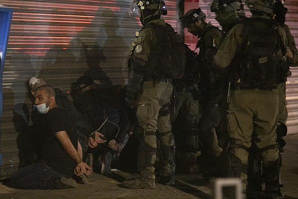 Israeli officers blindfold a Palestinian citizen of Israel during violent confrontations in Lydd, central Israel. (Oren Ziv)