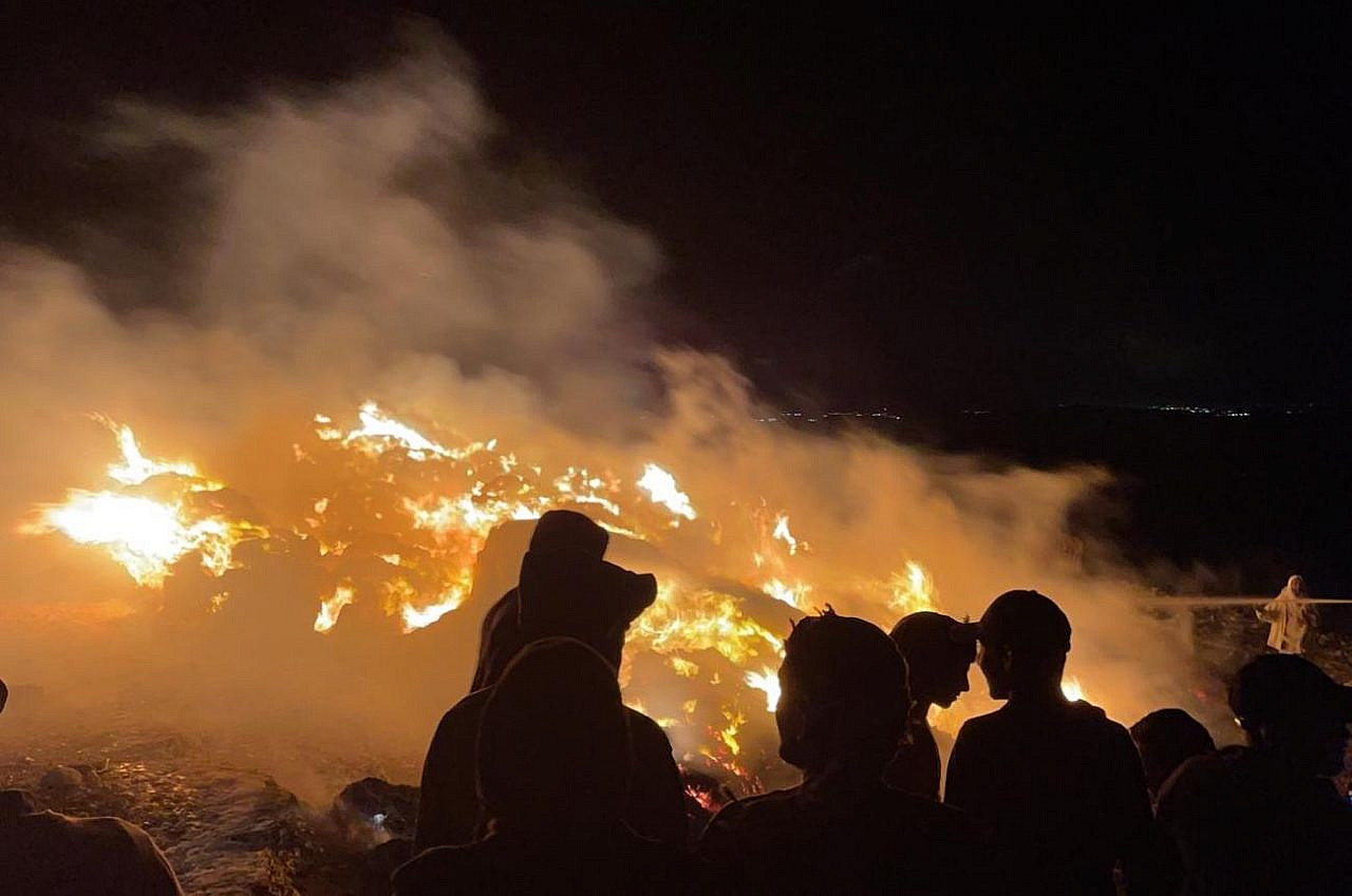 Palestinians in the village of Tuba in the South Hebron Hills look on after settlers set fire to their hay bales, June 1, 2021. (Courtesy of Jaber Awad)