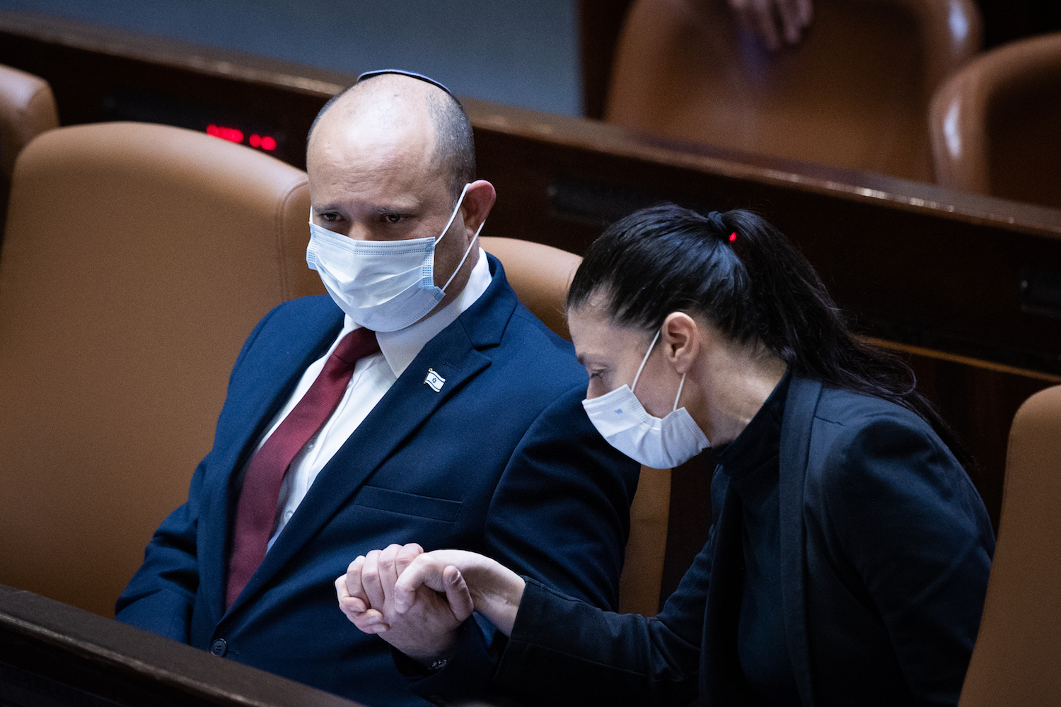 Naftali Bennett and Merav Michaeli hold hands during a debate on the Citizenship Law in the Knesset, July 6, 2021. (Yonatan Sindel/Flash90)