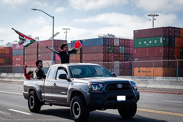 A Palestine solidarity activist hoists the Palestinian flag as demonstrators move to block an Israeli-owned ship at the Port of Oakland, in protest of Israel's aggressions, June 4, 2021. (Brooke Anderson)