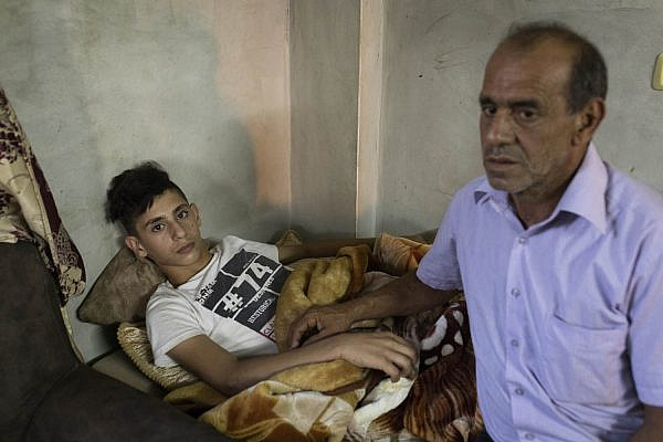 Tareq Zbeideh (left) and his father Abed a-Razeq seen in their family home after Tareq was abducted and brutally attacked by settlers near the former settlement of Homesh, Silat a-Dahr, West Bank. (Oren Ziv)