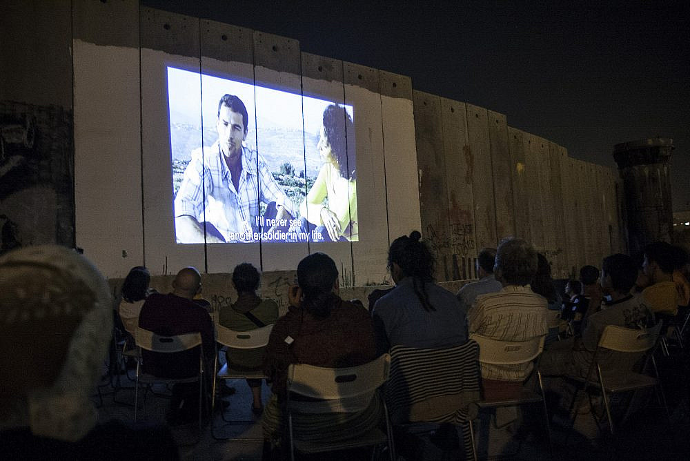 Palestinians watch a film screened on the Israeli Separation Wall as part of a festival, Aida refugee camp, Aug. 29, 2008. (Anne Paq/Activestills)
