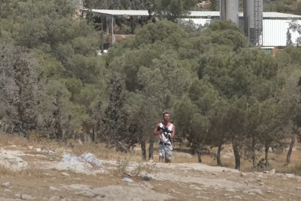 A settler fires at Palestinians from the village of a-Tuwani in the South Hebron Hills using a weapon he had grabbed from an Israeli soldier, June 26, 2021. (Screenshot from video by B'Tselem)