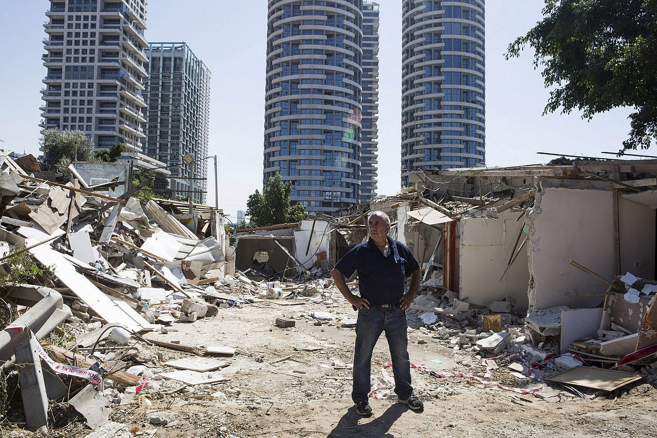 Kaduri Halif stands between the rubble of his destroyed home, Givat Amal, Tel Aviv, September 18, 2014. (Keren Manor/Activestills)