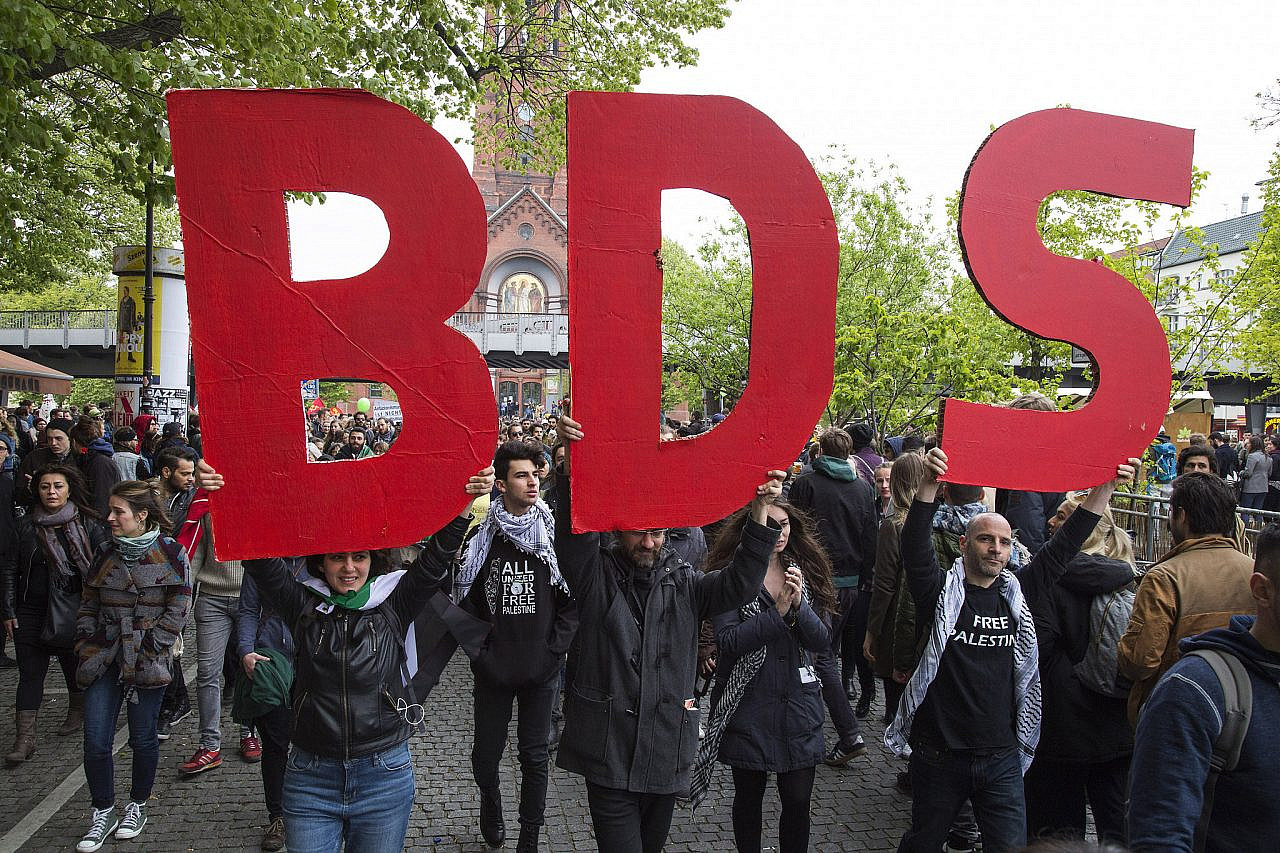 Activists holding a BDS sign march as part of the International Block during the May Day demonstration in Berlin, Germany, May 1, 2017. (Keren Manor/Activestills)