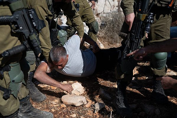 Israeli soldiers hold down prominent Palestinian activist Mohammad Khatib during the olive harvest near a settlement outpost established on Palestinian land in the Salfit area of the West Bank, October 11, 2021. (Matan Golan)