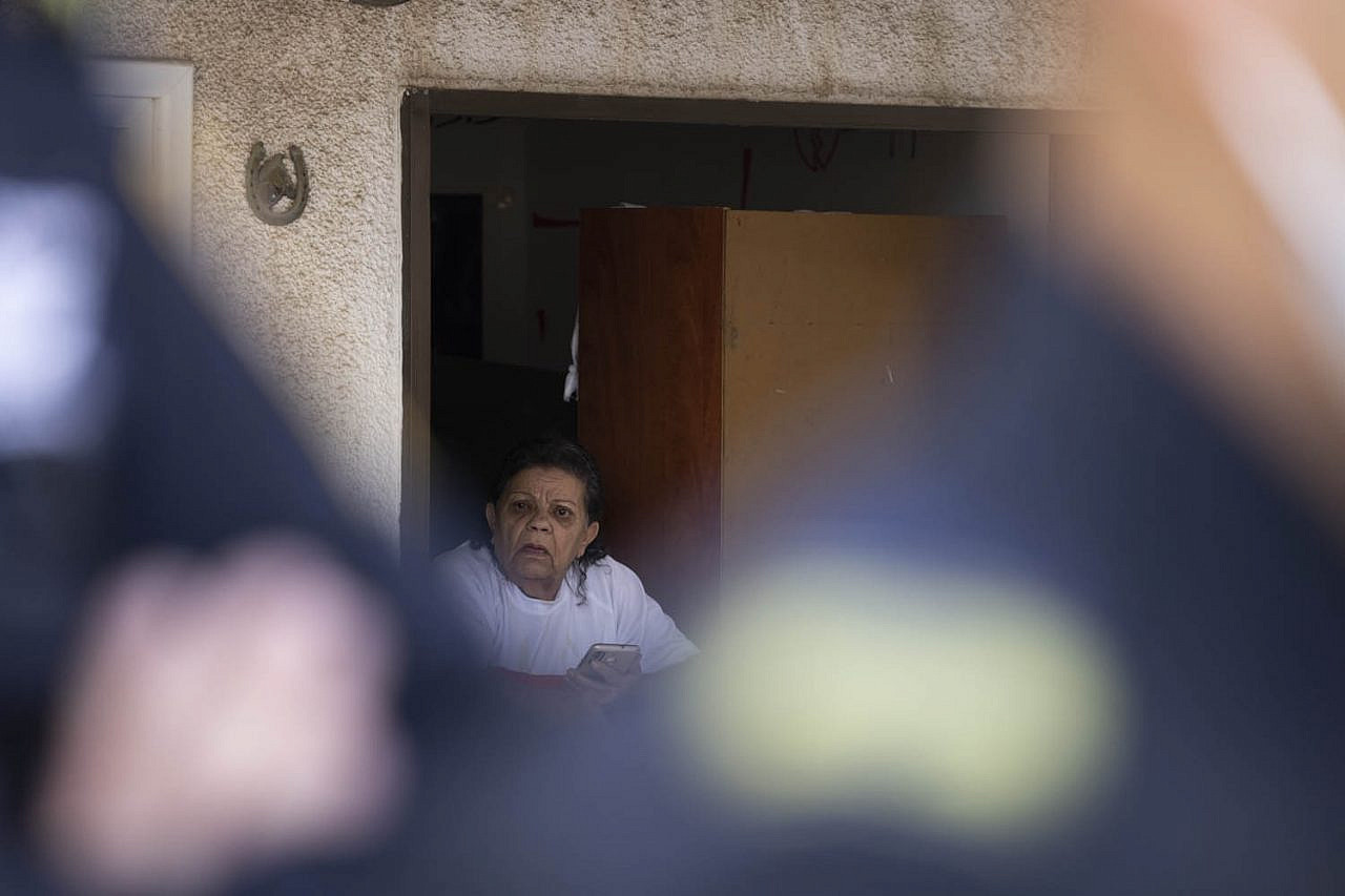 Levana Ratzabi looks out of the window of her home as police evict residents of her neighborhood, Givat Amal, Tel Aviv, November 15, 2021. (Oren Ziv/Activestills.org)
