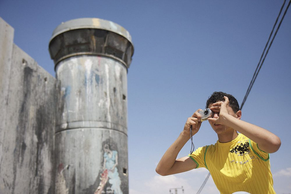 A Palestinian takes a picture near the separation wall in Aida refugee camp as part of a photography program for young Palestinian refugees, May 23, 2009. (Anne Paq/Activestills)