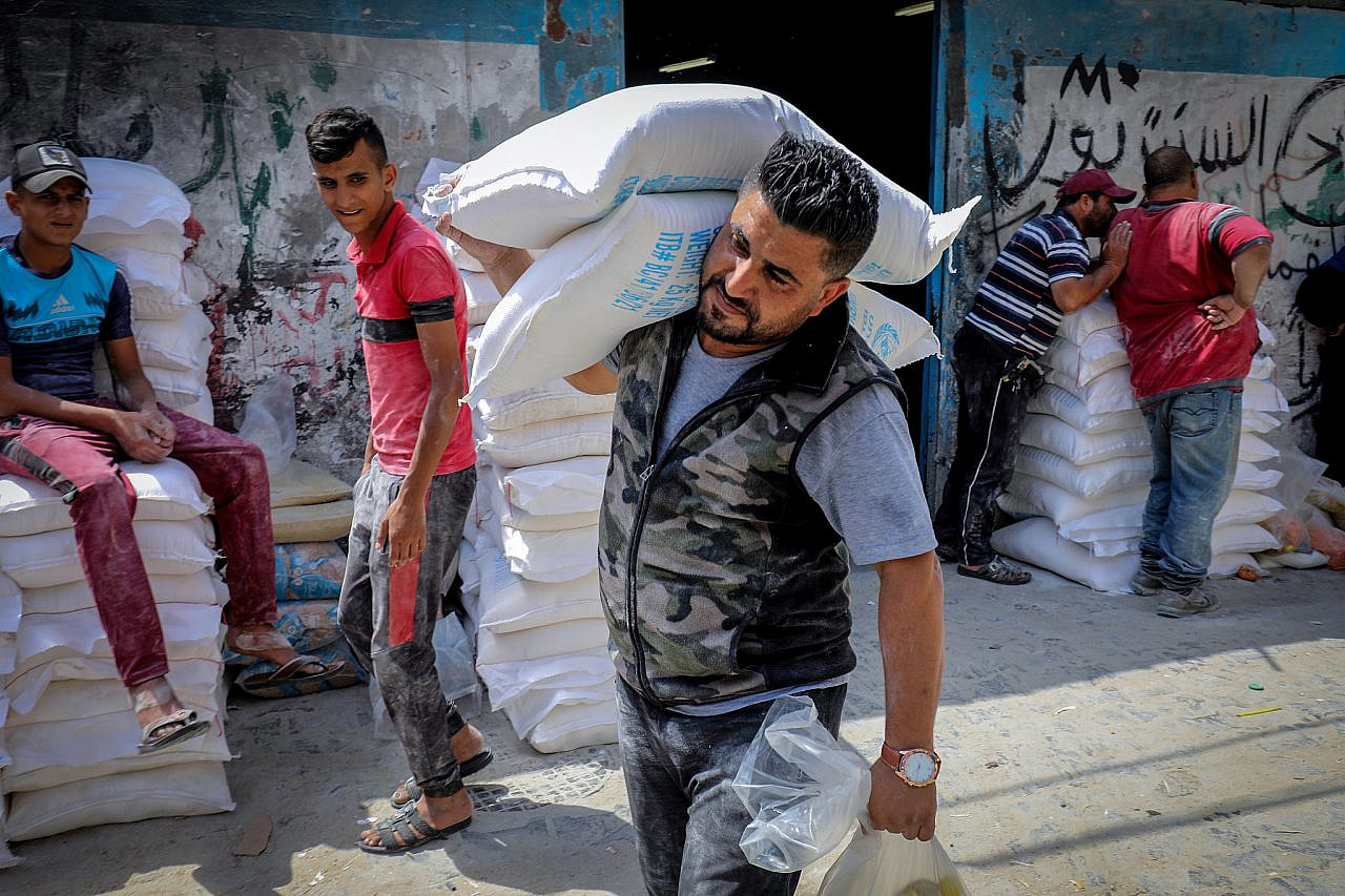 Palestinians receive food aid at a United Nations distribution center (UNRWA) in the Rafah refugee camp in the southern Gaza Strip, June 14, 2021. (Abed Rahim Khatib/Flash90)
