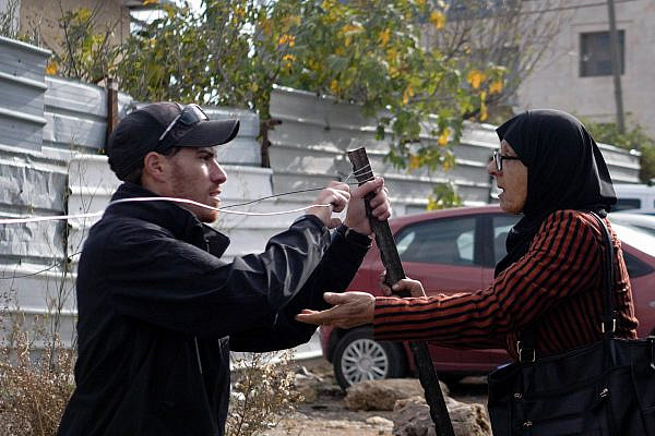 Fatma Salem argues with a Jewish settler setting up a metal fence outside her home in Sheikh Jarrah, Jerusalem, Dec. 16, 2021. (Rachel Shor)