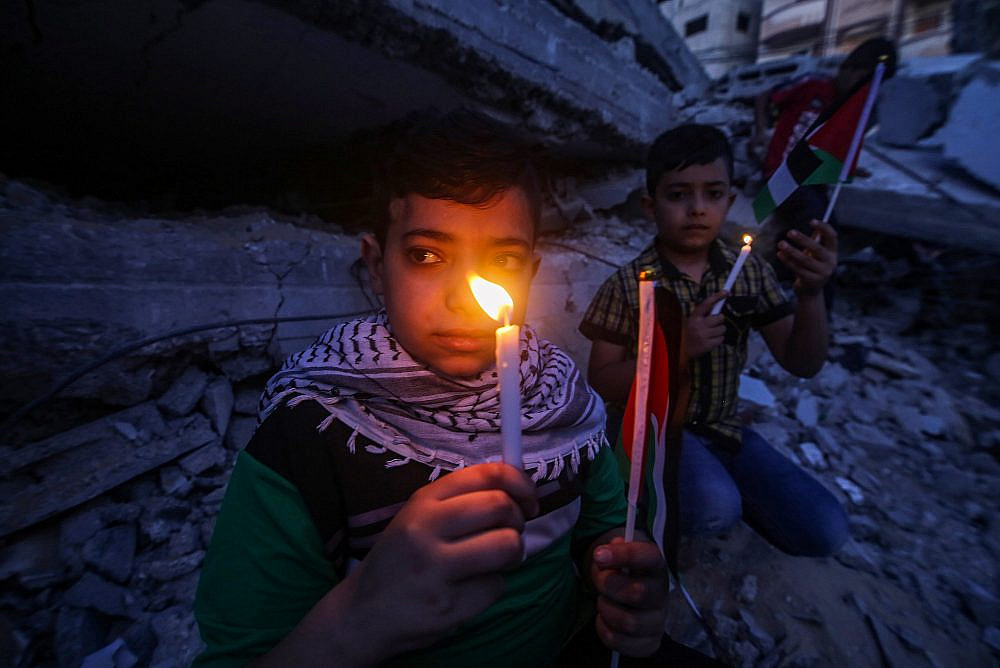 Palestinian children light candles during a protest near destroyed buildings in the southern Gaza Strip city of Rafah, May 25, 2021. (Abed Rahim Khatib/Flash90)