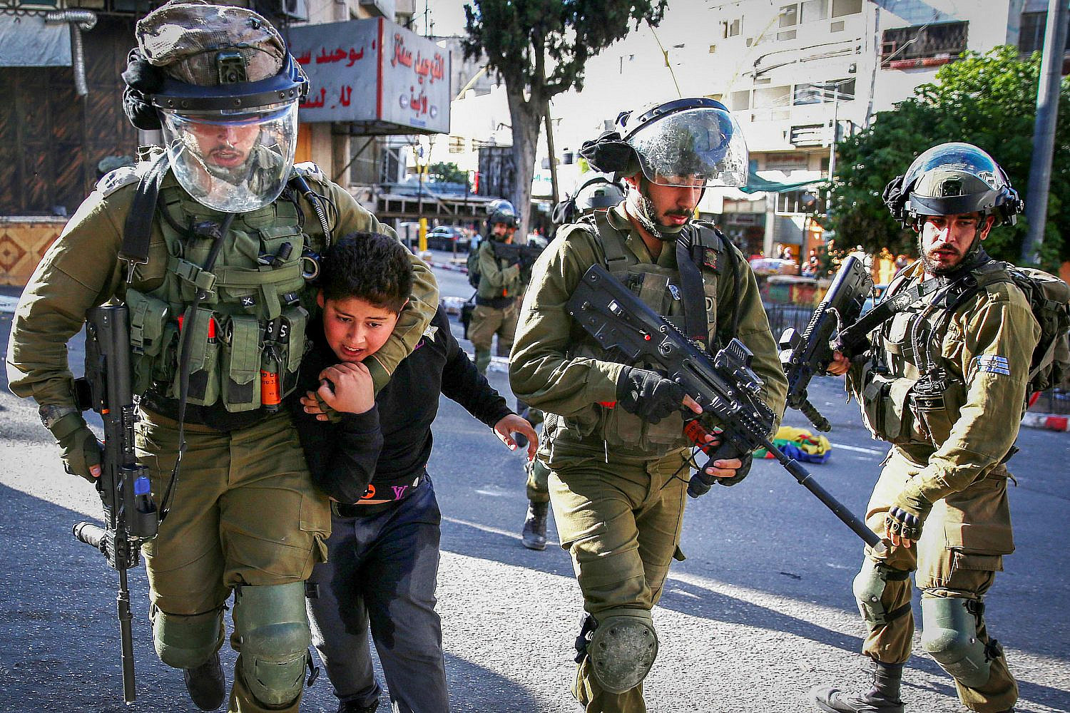 Israeli soldiers arrest a Palestinian boy as Jew-Israelis tour in the West Bank city of Hebron, during the Jewish holiday of Sukkot, September 23, 2021. (Wisam Hashlamoun/Flash90)