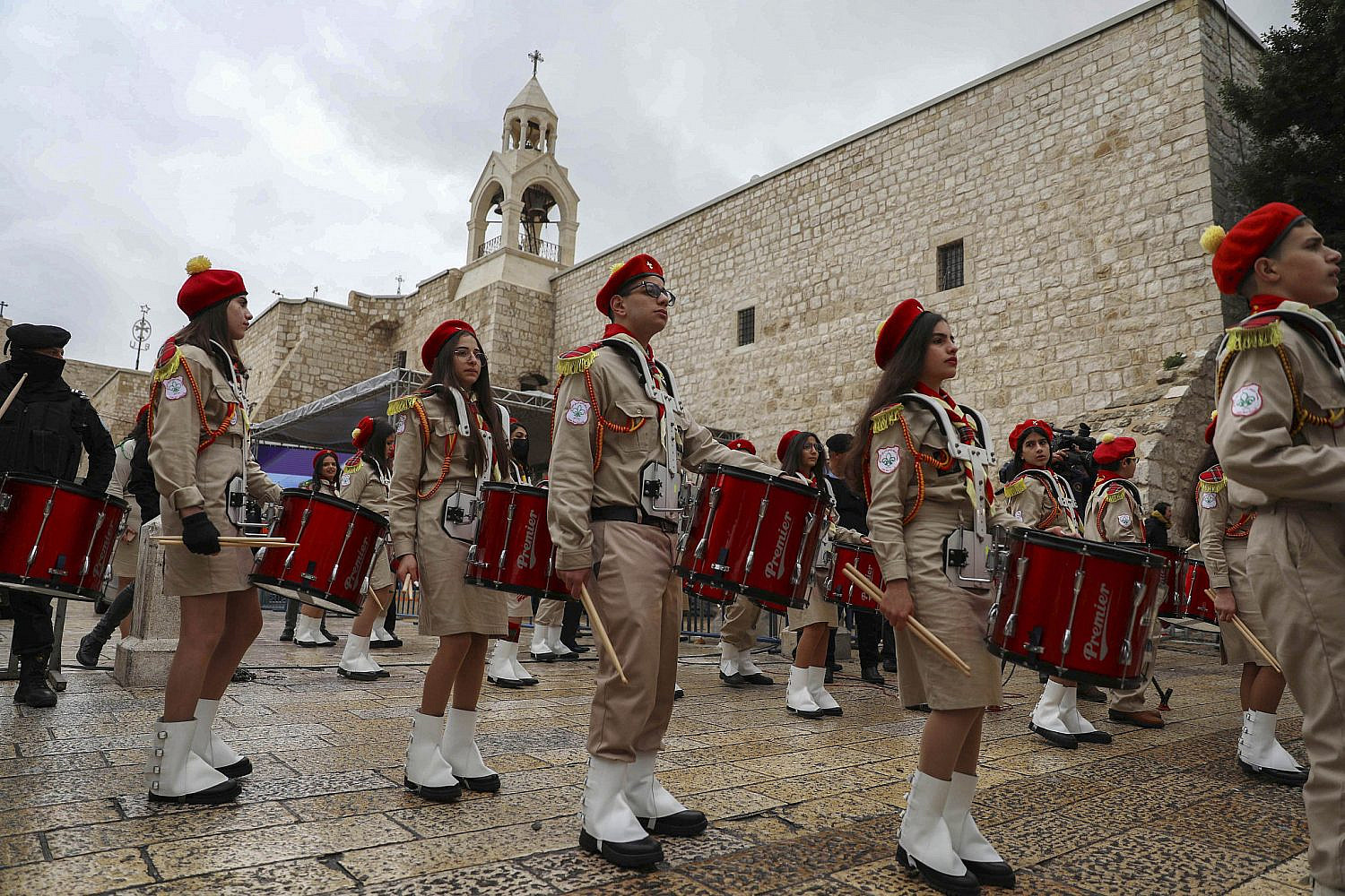 Palestinian scouts participate in a parade as Latin Patriarch Pierbattista Pizzaballa, the top Catholic clergyman in the Holy Land, center, arrives to the Church of the Nativity ahead of the midnight Christmas Mass, in the West Bank town of Bethlehem, Friday, Dec. 24, 2021. (Wisam Hashlamoun/Flash90)