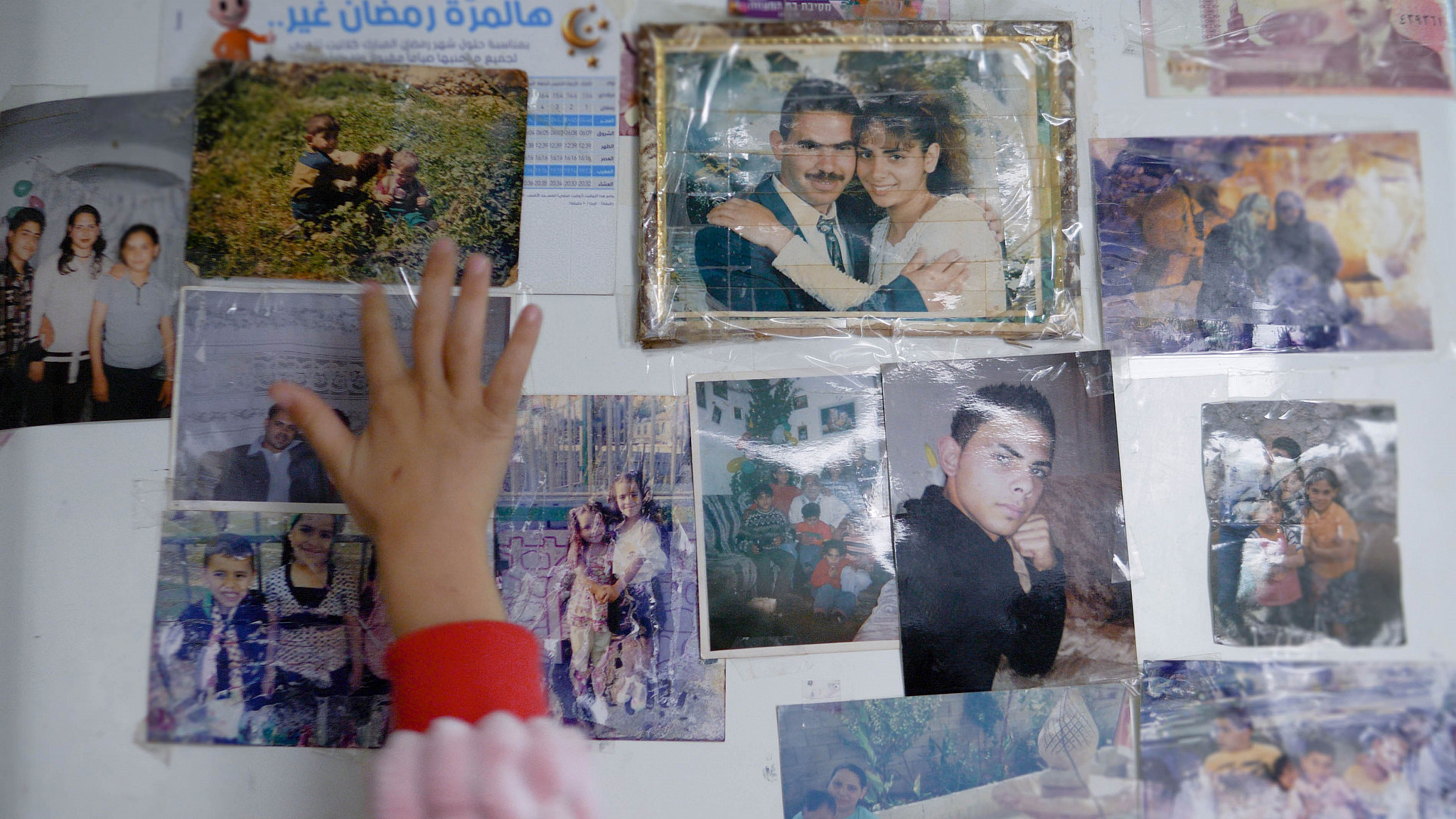 Young Fatma places her hand over pictures on the fridge in the Salem family home in Sheikh Jarrah, Jerusalem, Dec. 16, 2021. (Rachel Shor)
