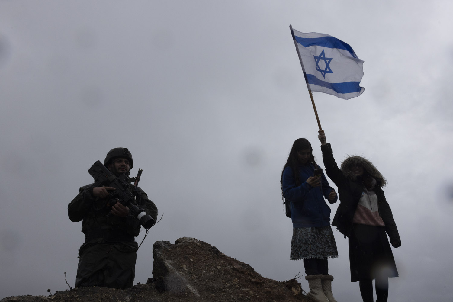 Settlers wave an Israeli flag during a march near the settler outpost of Homesh, following the murder of a settler there, December 23, 2021. (Oren Ziv)
