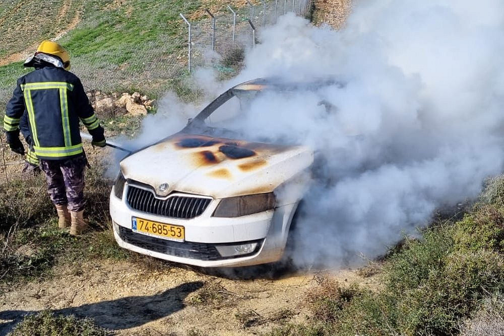 A Palestinian firefighter puts out a blazing car that had been set on fire by settlers in the Palestinian village of Burin, West Bank, January 21, 2022. (Courtesy of Yesh Din)