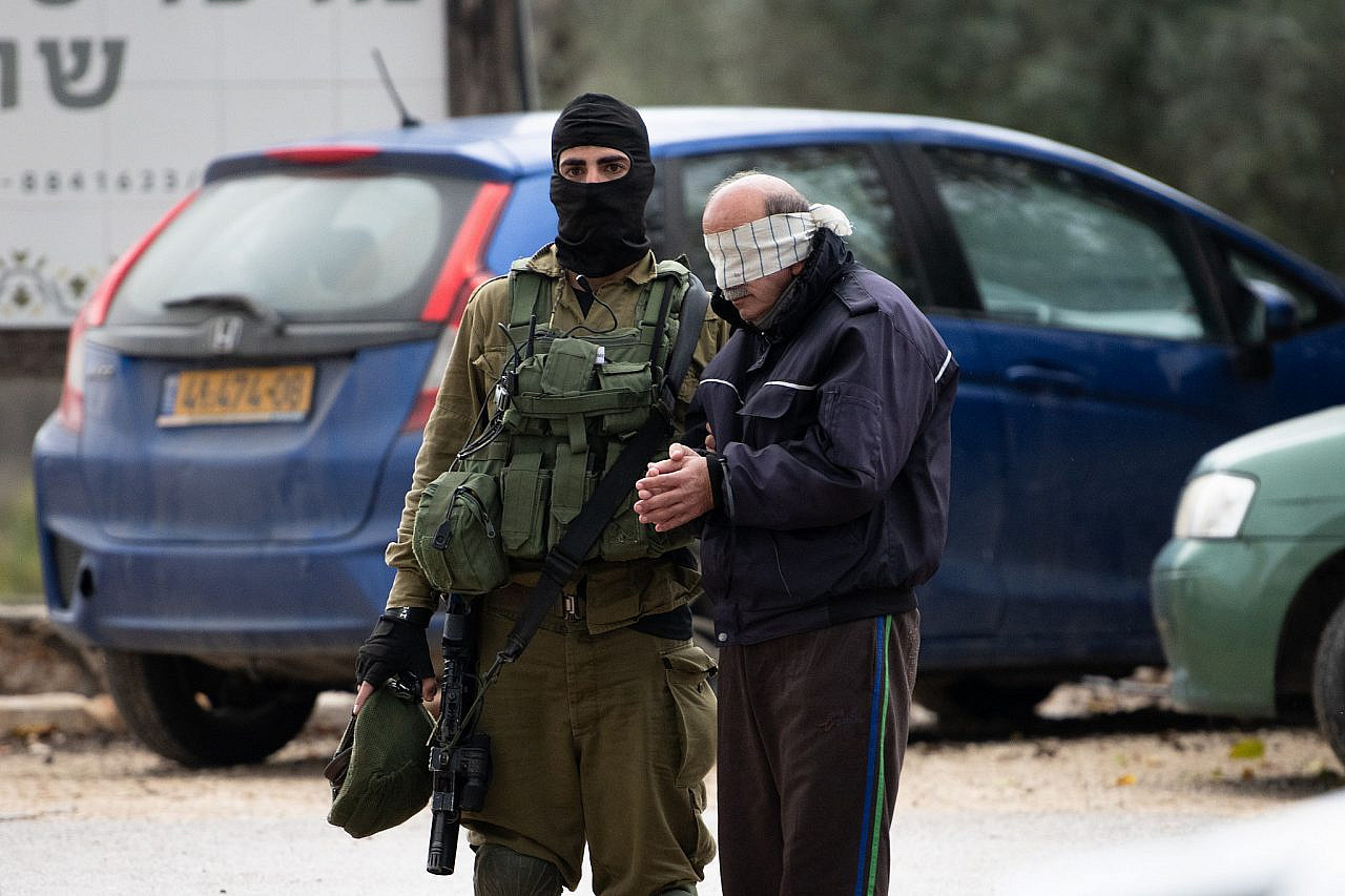 Israeli soldiers arrest a Palestinian man outside the West Bank settlement of Shavei Shomron, December 17, 2021, following the shooting attack near Homesh. (Sraya Diamant/Flash90)