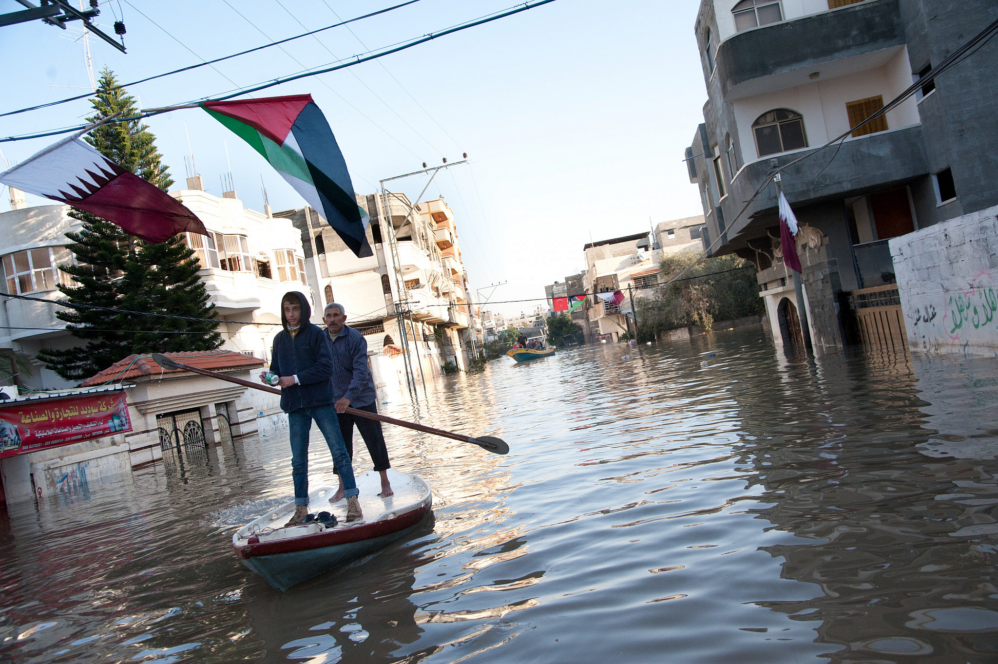 A week after torrential rain caused severe flooding, Palestinians use fishing boats to assist residents in retrieving belongings from their homes in the Al-Nafaq section of Gaza City, December 18, 2013. (Ryan Roderick Beiler/Activestills.org)