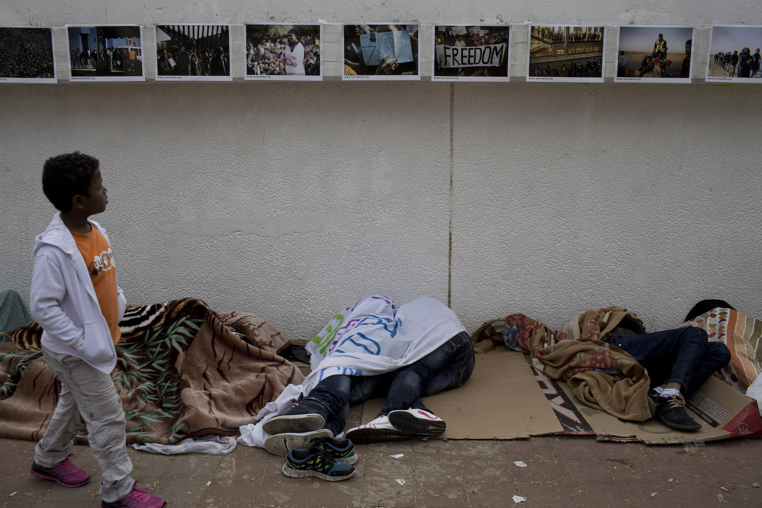 African asylum seekers sleep near an Activestills photo exhibition on the asylum seekers' struggle in Israel, Levinsky Park, South Tel Aviv, February 4, 2014. (Oren Ziv)